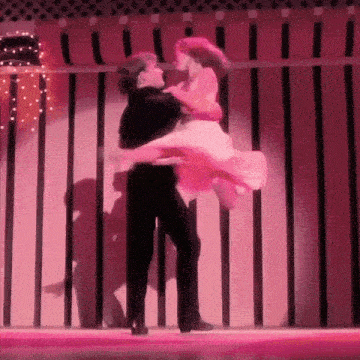 a man and a woman are dancing on a stage in front of a pink curtain .