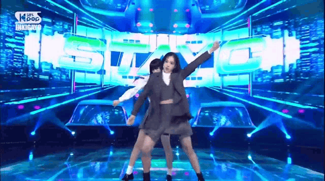 two women are dancing on a stage in front of a sign that says kpop