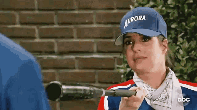 a woman wearing a blue hat is holding a bat .