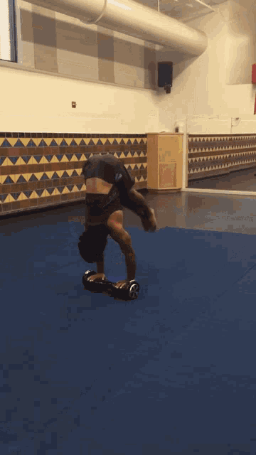 a person doing a handstand on a blue mat in a gym