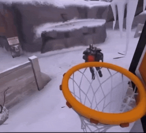 a man is jumping through a basketball hoop in a snowy area
