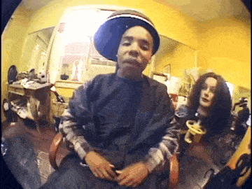 a man wearing a hat is sitting in a chair next to a woman holding a baby .