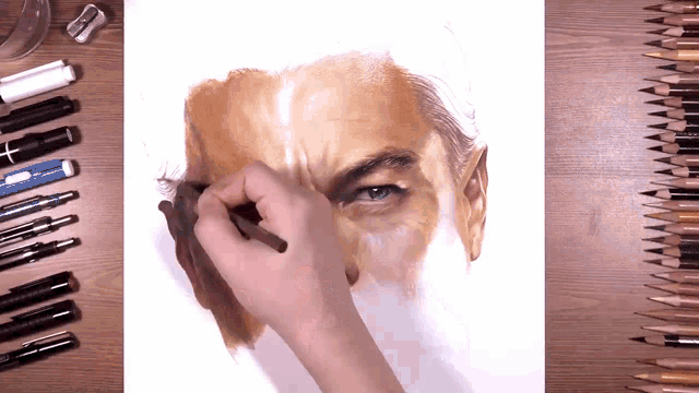 a person is drawing a man 's face with colored pencils on a wooden table