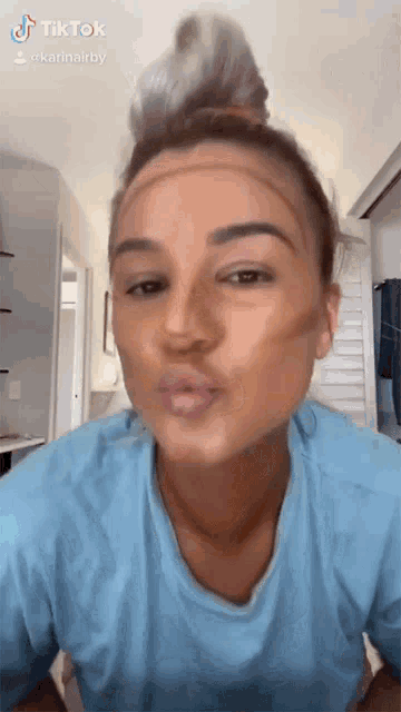 a woman wearing a blue shirt is making a funny face with a tiktok sticker
