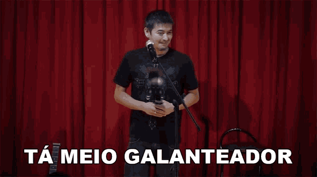 a man is singing into a microphone with the words ta meio galanteador behind him