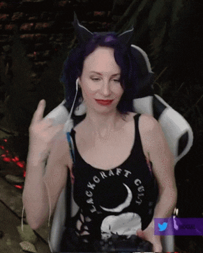 a woman with purple hair wearing a black tank top that says blackcraft guilt