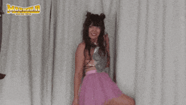 a woman in a pink skirt is standing in front of a white curtain with the word madman written on it