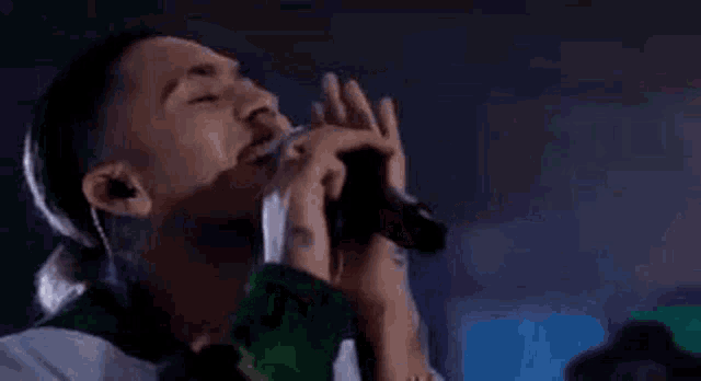 a man is singing into a microphone while wearing ear buds .