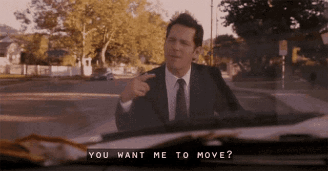 a man in a suit and tie is pointing at the camera with the words " you want me to move " above him