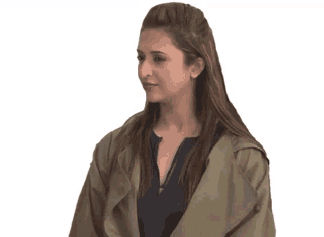 a woman wearing a green jacket and a blue shirt looks to the side