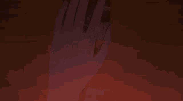 a close up of a person 's hand in a dark room with a red background .