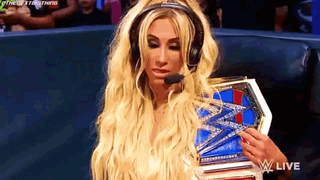 a woman wearing headphones and holding a wrestling championship belt