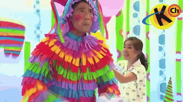 a man in a colorful costume is standing next to a girl in a white shirt .