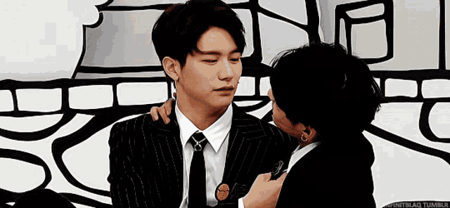 two men in suits and ties are hugging each other .