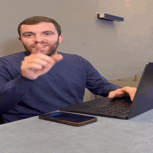 a man sitting at a table with a laptop and cell phone