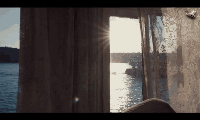the sun is shining through a window with a view of the ocean