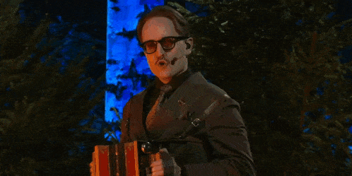 a man with glasses and a mustache is wearing a suit and tie and a microphone