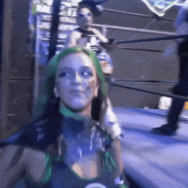 a woman with green hair is in a wrestling ring with other women