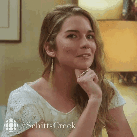 a woman wearing a white shirt with #schitts creek written on the bottom
