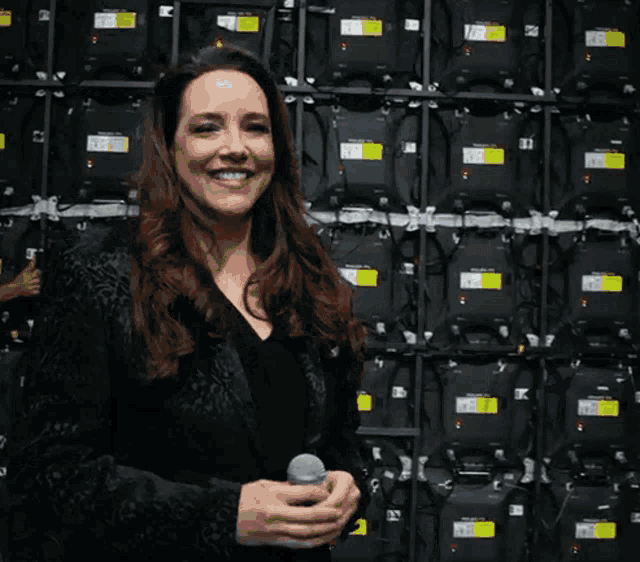 a woman stands in front of a wall of boxes with a yellow sticker on it