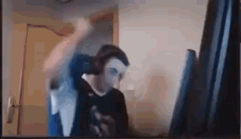 a man wearing a mask is standing in front of a computer monitor .