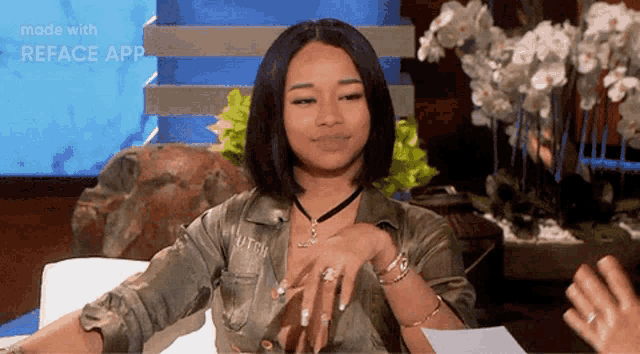 a woman in a green shirt is sitting in a chair with her hands folded