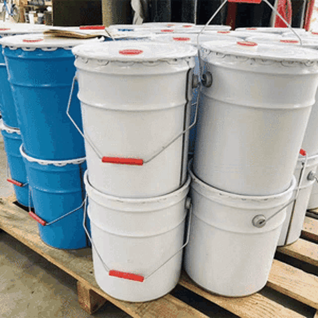 blue and white buckets with red handles are stacked on top of each other on a wooden pallet