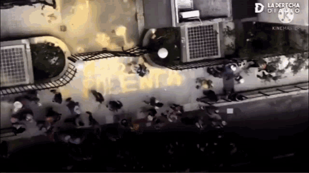 an aerial view of a group of people standing in front of a building with the word menta painted on the sidewalk
