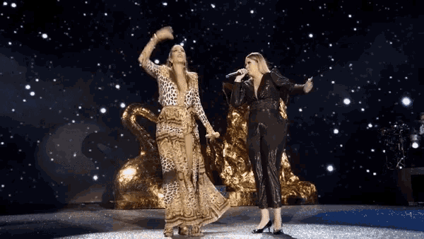 two women singing on a stage in front of a starry sky