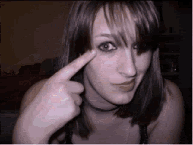 a woman is pointing at her eye and making a funny face