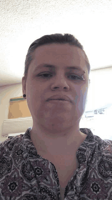 a woman wearing a paisley shirt has a nose ring