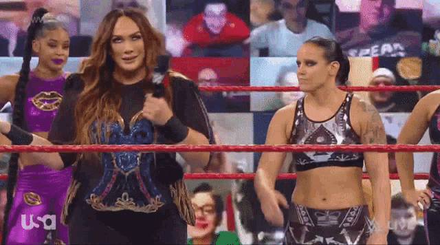 a group of women are standing in a wrestling ring and one of them has the word usa on her shirt