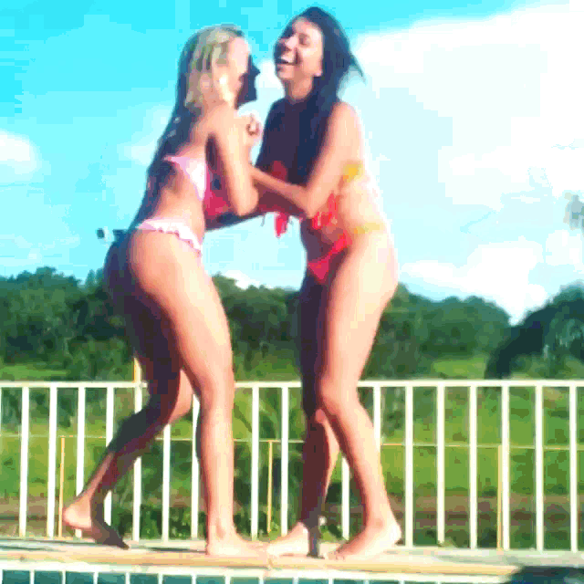 two women in bikinis are standing next to each other on a balcony