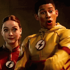 a man and a woman are standing next to each other wearing superhero costumes .