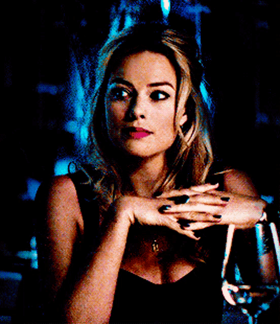 a woman in a black dress with a gold necklace has a ring on her left hand