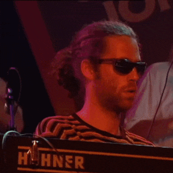 a man wearing sunglasses playing a hohner keyboard