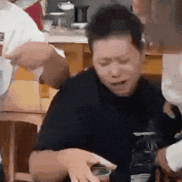a man in a black shirt is sitting at a table with a glass of water .
