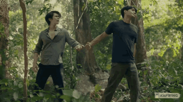 two men holding hands in the woods with kapwing written on the bottom