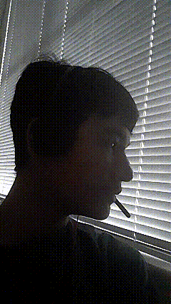 a man is smoking a cigarette in front of a window
