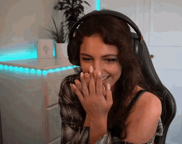 a woman wearing headphones and a plaid shirt is laughing