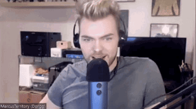 a man wearing headphones is talking into a microphone while looking at the camera .