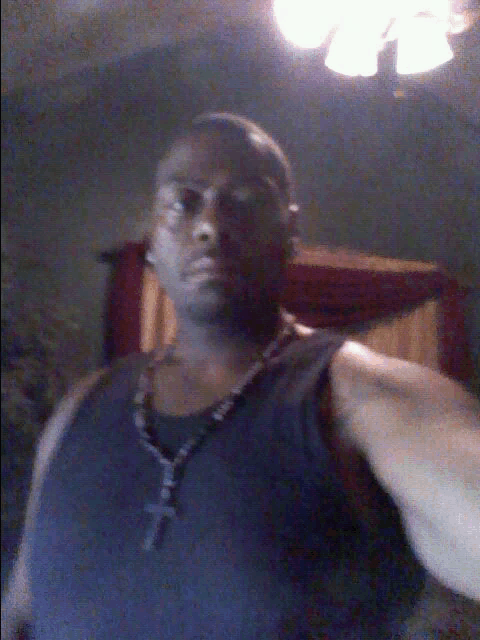a man wearing a black tank top with a cross necklace