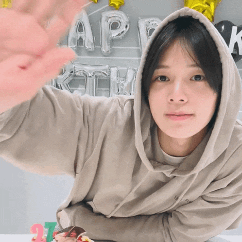 a person wearing a hoodie with the number 27 on a cake in front of them
