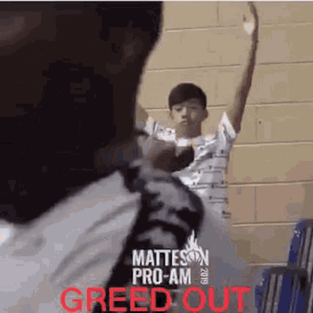 a man is standing in front of a brick wall holding a basketball while another man watches .