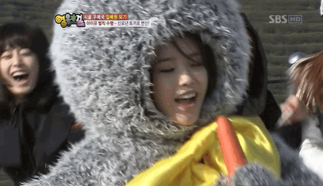 a woman is wearing a furry hooded jacket and holding a yellow ribbon ..
