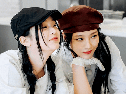 two women wearing hats are looking at each other with one wearing a black hat