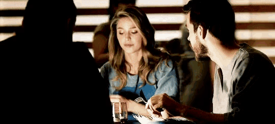 a man and a woman are sitting at a table in a restaurant . the woman is holding a knife and fork .