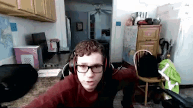 a young man wearing glasses and headphones is standing in a messy room .