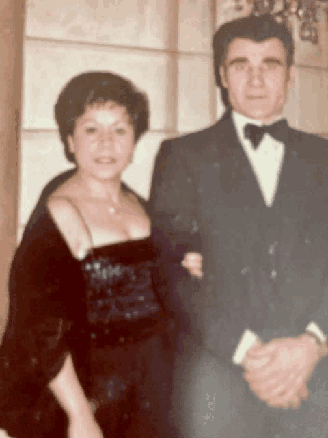 a man in a tuxedo and a woman in a dress pose for a photo