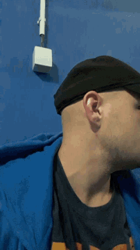 a man wearing a black hat and a black shirt is laying on a blue blanket